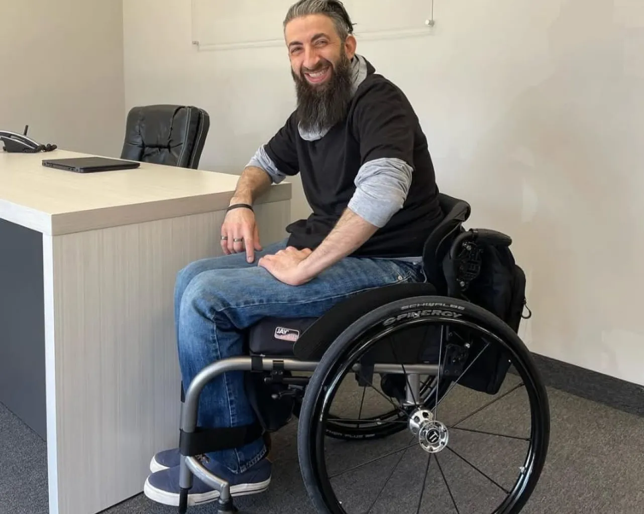Terry, wearing a black shirt and blue jeans, sitting in a wheelchair.
