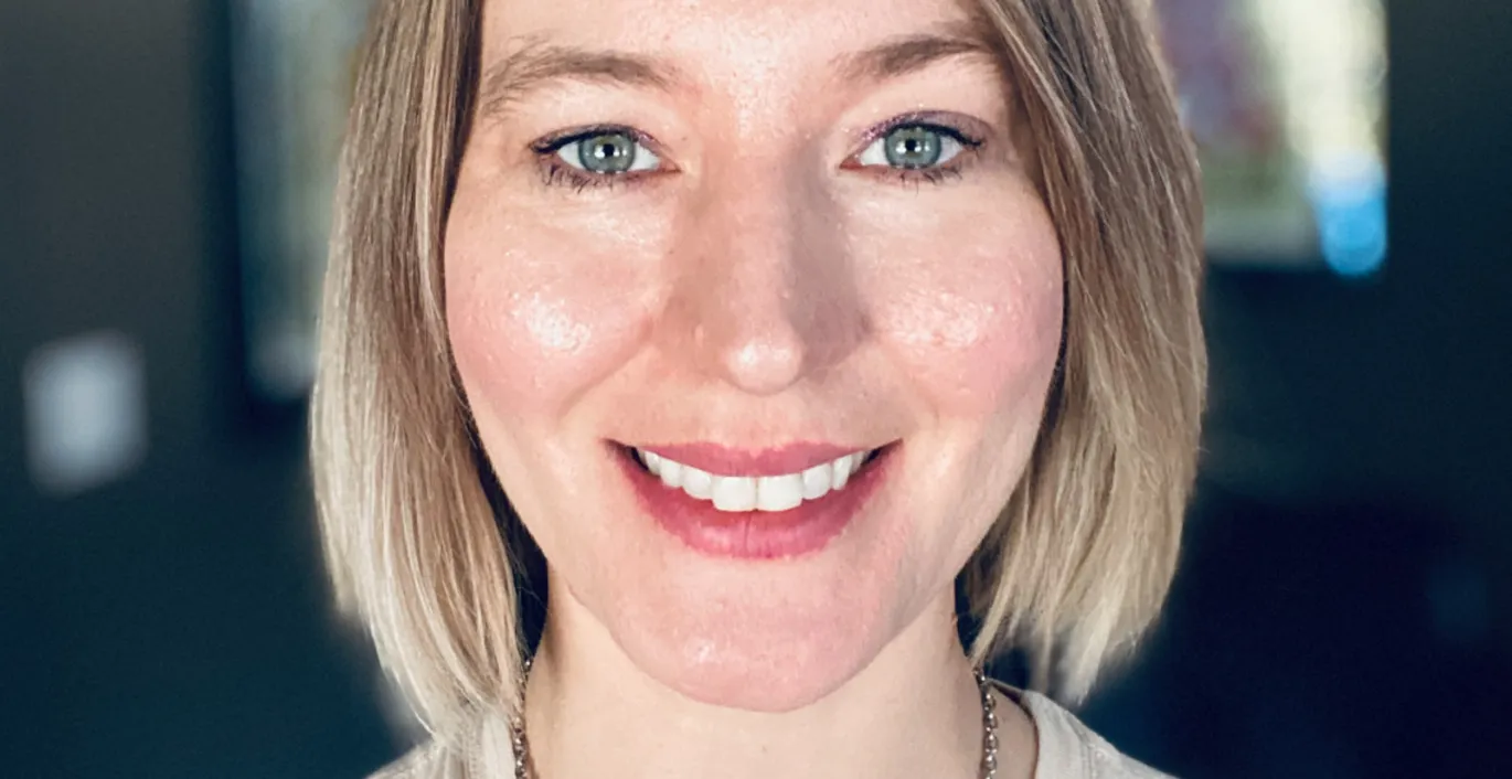 Jaclyn with short blonde hair wearing a casual top, photographed indoors.