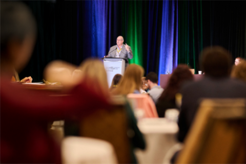 A man addresses an audience from a podium.