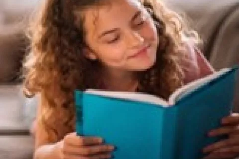 A child with long curly hair reading.