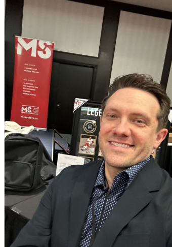 Brent wearing a black suit, in front of a MS Canada sign.