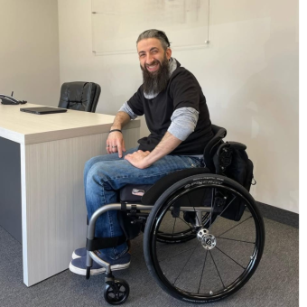 Terry, wearing a black shirt and blue jeans, sitting in a wheelchair.