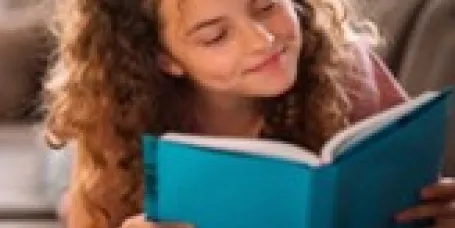 A child with long curly hair reading.