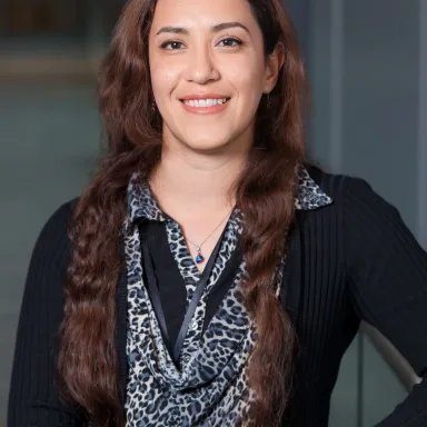 Dr. Rayatpour, wearing a black top, with long brown hair.