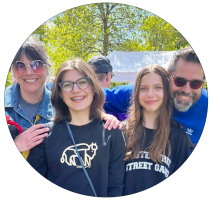 Four people smiling outdoors on a sunny day.
