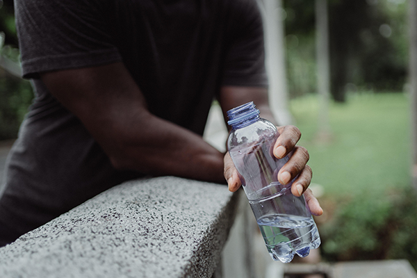 A man leaning and holding a water bottle.