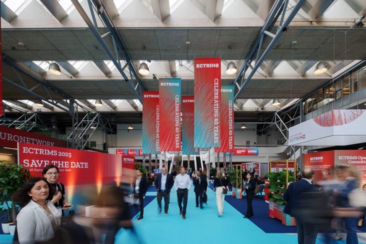 [ECTRIMS meeting hall with welcome banners, industry booths, and people networking]