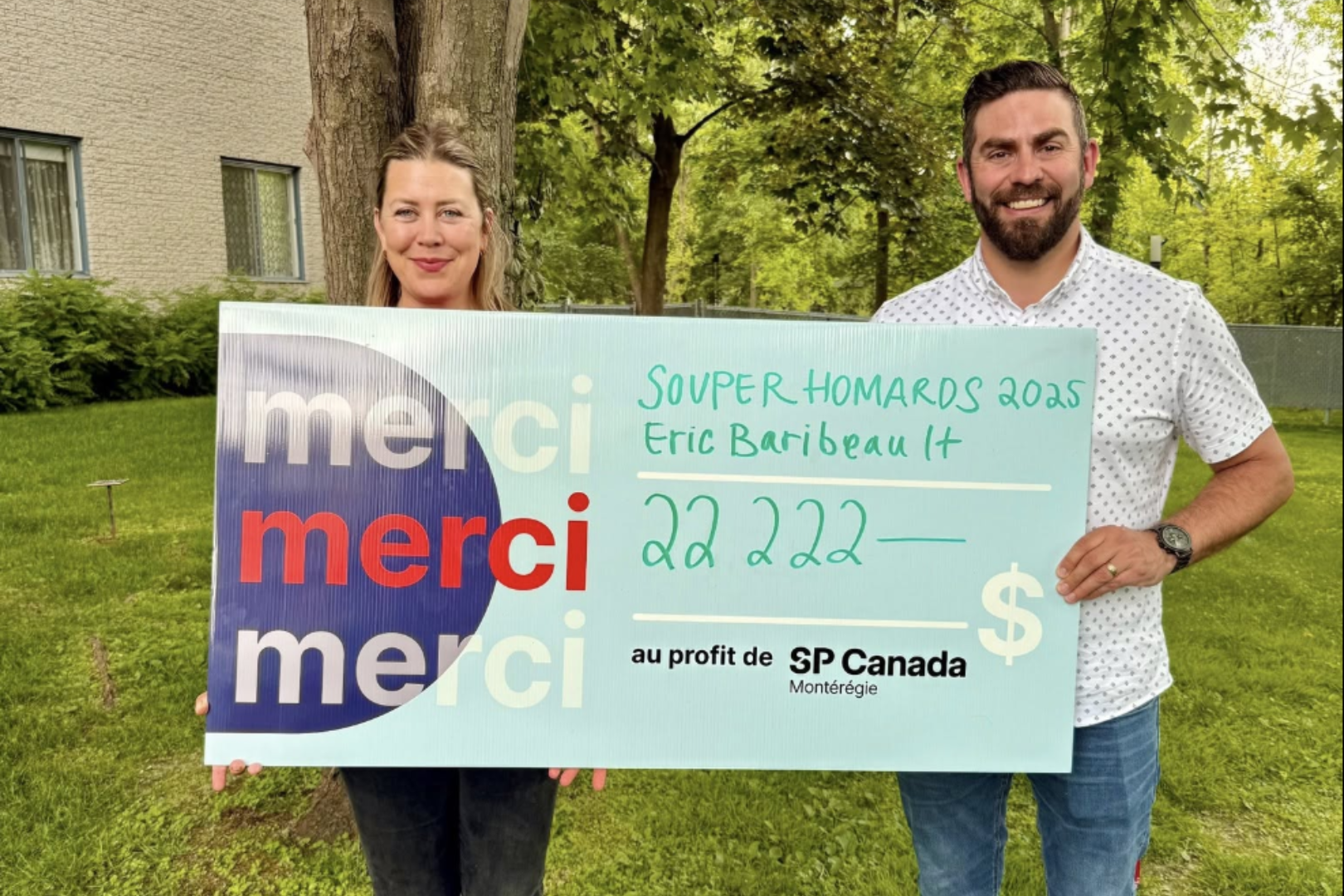 Un couple portant un chèque de dons, un arbre