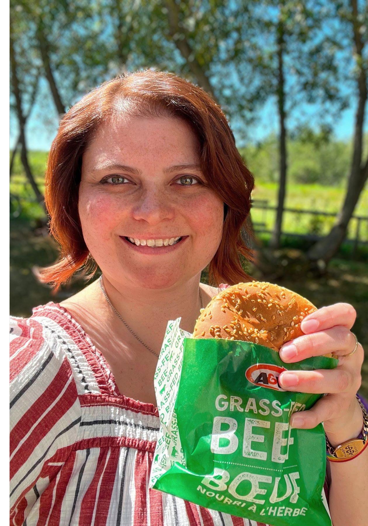 Caitlin holding a Teen Burger® outside with trees in the background