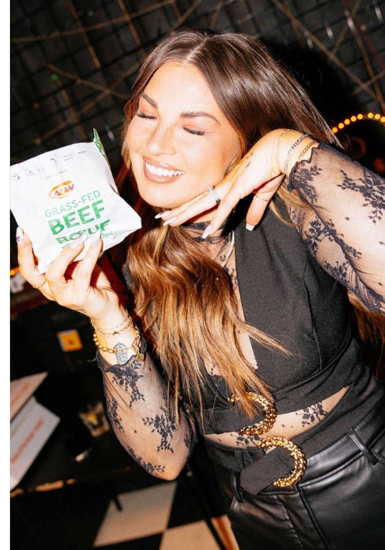 Jess Moskaluke wearing a black shirt and black pants, smiling and holding a Teen Burger®
