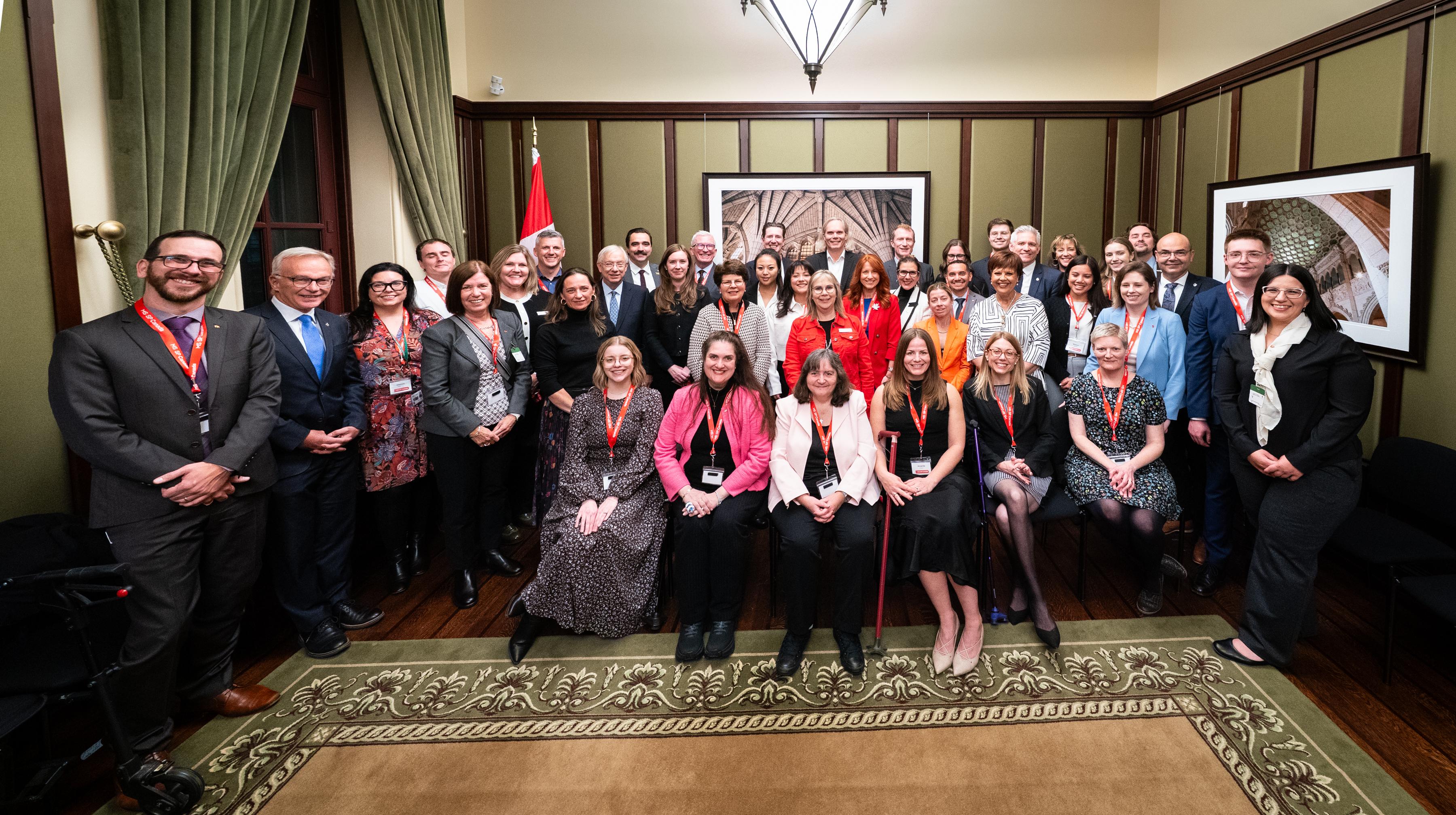 Large group of formally dressed people posing together indoors for an official group photo.
