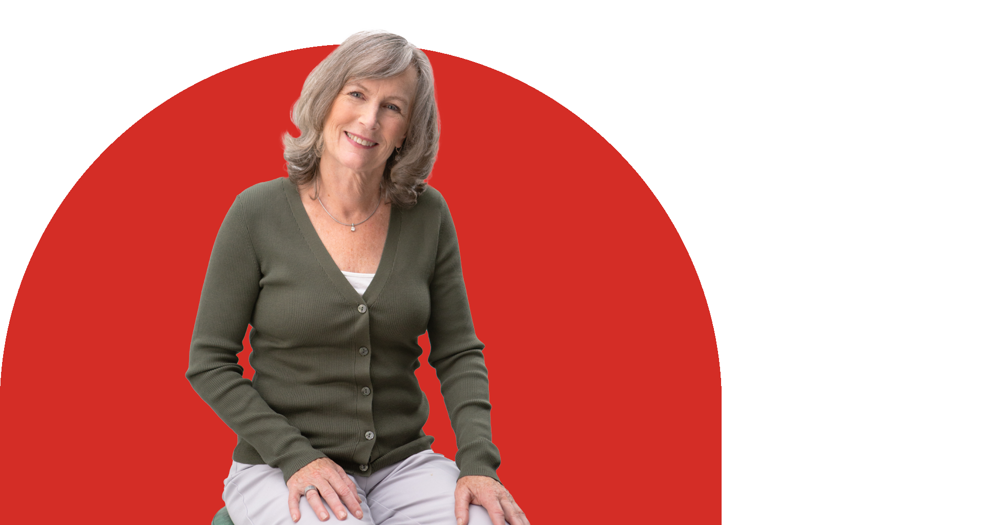 Middle-aged woman in a green cardigan sitting casually against a bold red circle background.