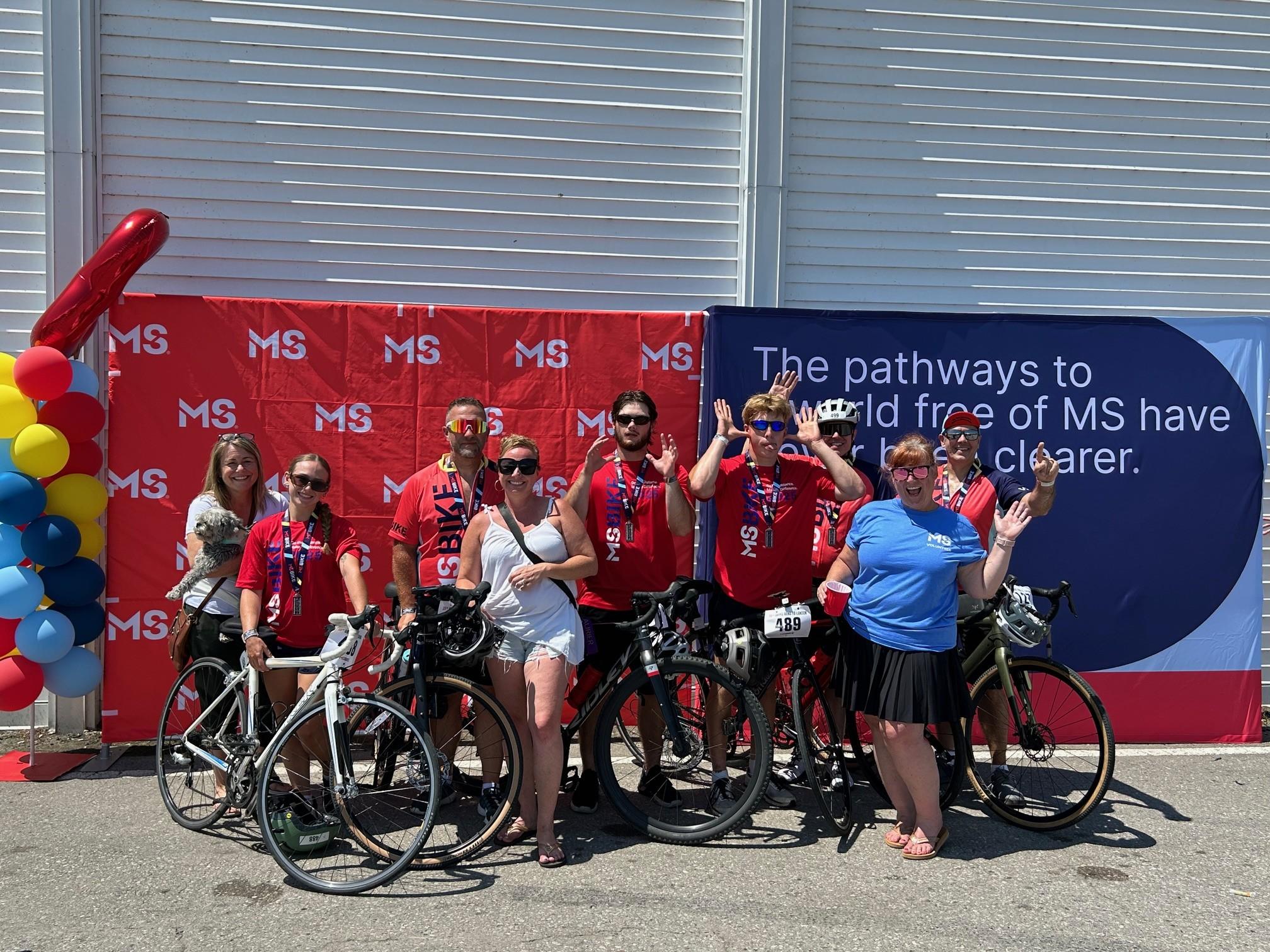 Andrea and MS Bike participants posing with bikes in front of an MS Canada banner.