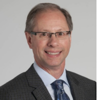 Professional headshot of a middle-aged man in a gray suit and tie, wearing glasses.