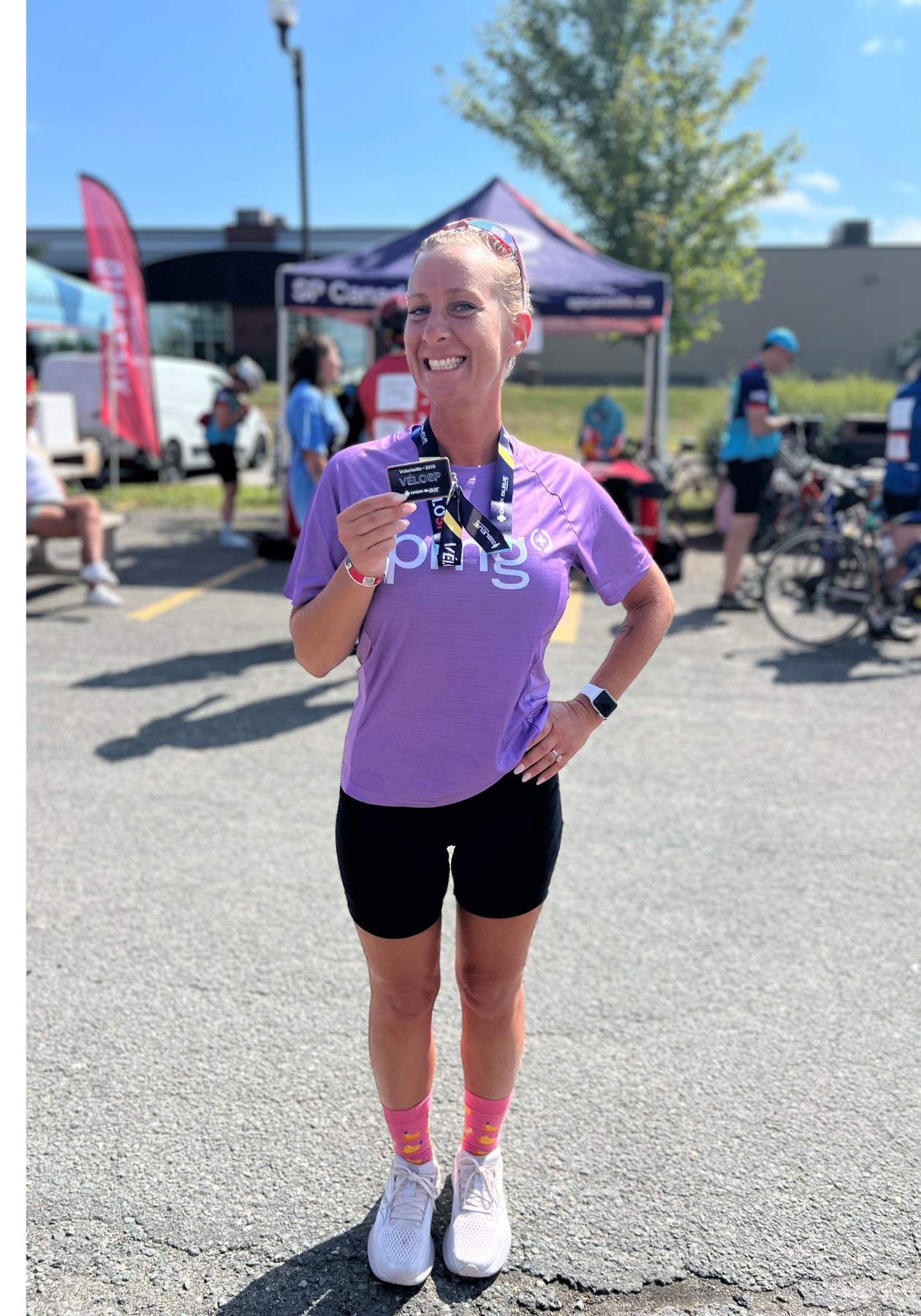 Chantal in a purple PMG shirt smiling at an MS Bike event with a medal around her neck.