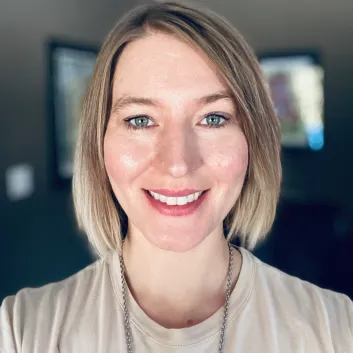 Jaclyn with short blonde hair wearing a casual top, photographed indoors.